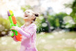 © Tom Wang - happy little girls playing water guns in the park.