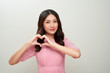 Pretty young asian woman making a heart gesture with her fingers in front of her chest