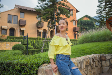 asian girl wearing yellow shirt and jeans posing in emotional smile happy with blur village countryside style vintage