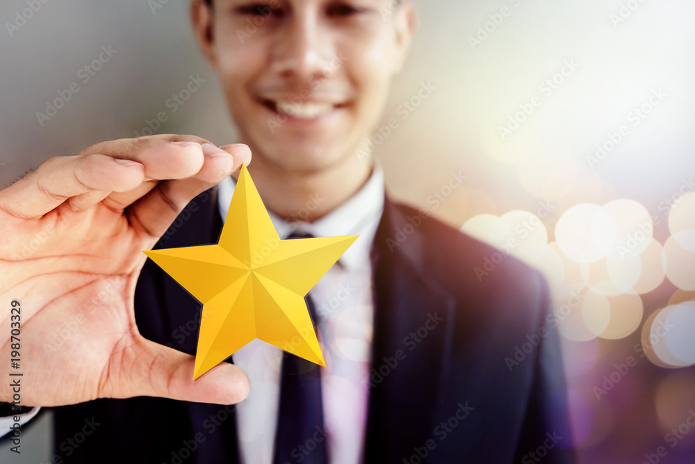 Success in Business or Personal Talent Concept. Happy Businessman in black suit Smiling and Showing a Golden Star in Hand - obrazy, fototapety, plakaty 