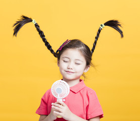 smiling little girl enjoying cool wind from electric fan