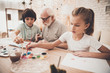 © freeograph - Grandfather, grandson and granddaughter at home. Children are painting with brushes.