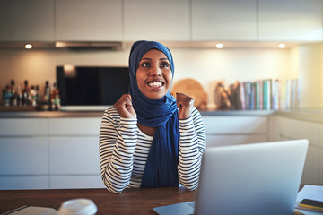 Wall Mural - Ecstatic young Arabic female entrepreneur working in her kitchen