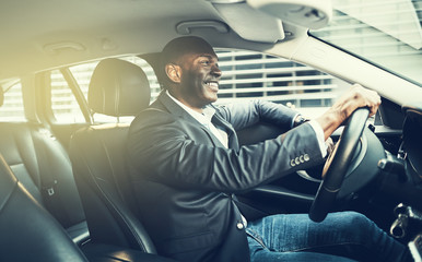 Sticker - Smiling African businessman driving his car through the city