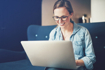 Young female entrepreneur sitting on a sofa working online