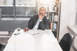 © Yakobchuk Olena - portrait of young respectable man sitting at cabinet and touching by arm to chin. He thoughtfully looking at camera while ready to sign a document