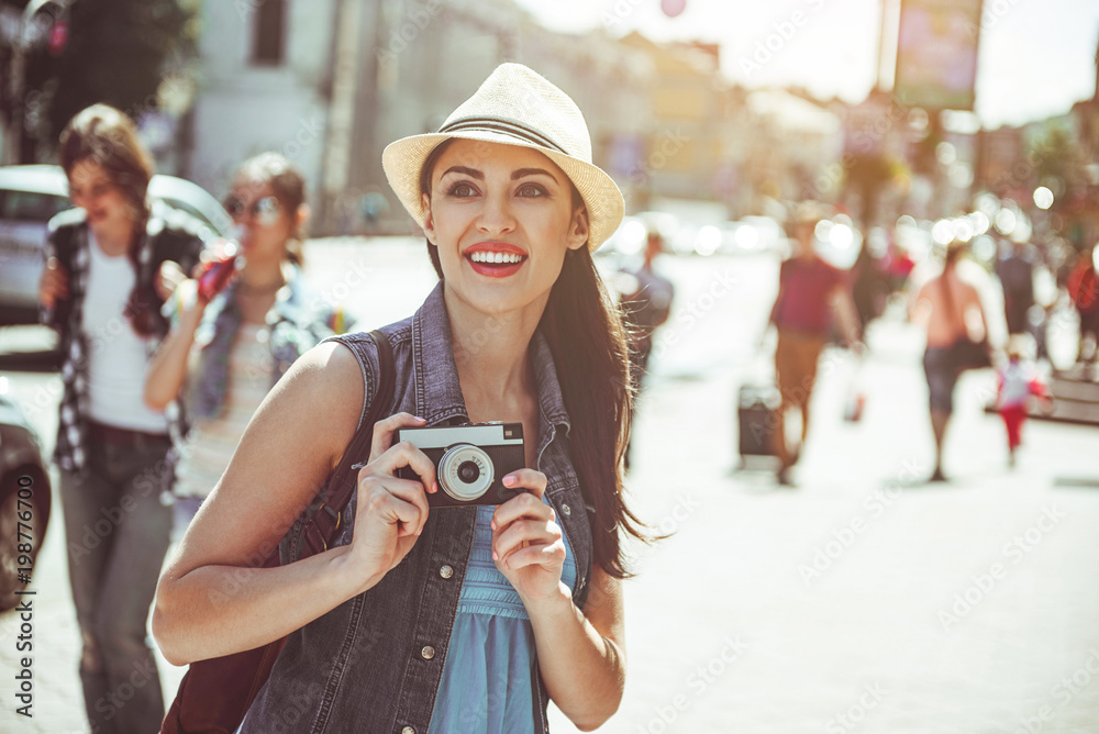 Portrait of pleased young woman doing images by camera while looking sightseeing. Glad tourist walking concept - obrazy, fototapety, plakaty 