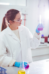 Wall Mural - young woman scientist working with laboratory glassware with different colors liquid in a laboratory