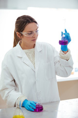 Wall Mural - young woman scientist working with laboratory glassware with different colors liquid in a laboratory