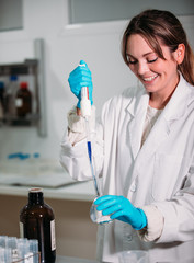Wall Mural - young woman scientist working with a pipette in a laboratory