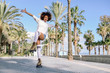 © javiindy - Black woman on roller skates rollerblading in beach promenade with palm trees