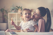 © Mladen - Cheerful  mother and little girl at home using laptop and having breakfast
