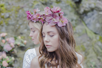 Fashion photo of a two beautiful young woman in a pretty dress with flowers posing outdoors 