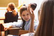 © burdun - Small pupils in the lesson. It's elementary school students. Girl diligently writes,. On a school desk there are textbooks and school accessorie