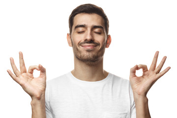 Concentrated relaxed man standing with closed eyes, having relaxation while meditating, trying to find balance and harmony. Yoga and meditation concept