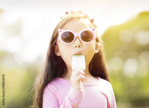 Foto Glückliches kleines Mädchen, das Popsicle an der Sommerzeit isst.