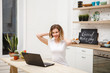 © Юлия Буракова - Portrait of a beautiful young woman with a laptop. Girl sitting at table in kitchen with laptop computer in white t-shirt