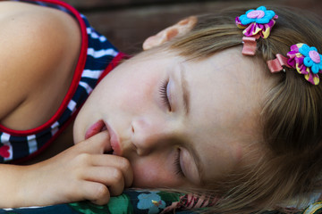 portrait of sleeping pretty child girl who sucks her finger while sleeping.