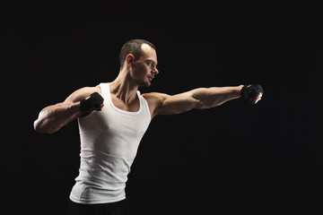 Wall Mural - Athletic man make punch on black background