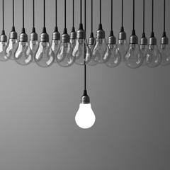 Fototapete - One hanging light bulb glowing different and standing out from unlit incandescent bulbs on dark grey background , leadership and different business creative idea concept. 3D rendering.