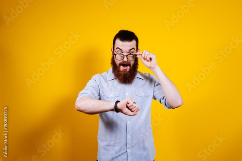 Fotografía Shocked bearded man in casual looking at watch