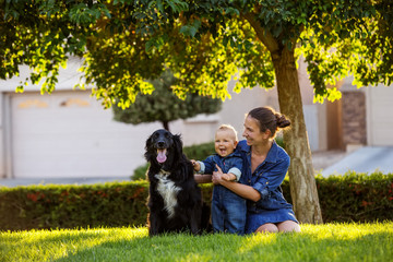 Wall Mural - A mother with baby son and black dog in green neighborhood