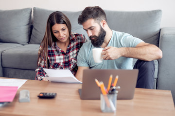 Young couple calculating bills at home