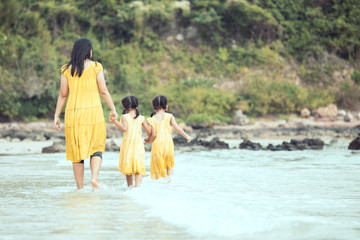 Wall Mural - Young asian mother and cute little daughter walking and playing together on beach in summer vacation