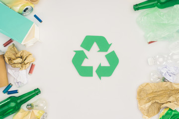 Wall Mural - top view of various types of trash surrounding recycle sign on white