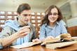 © Seventyfour - Positive satisfied school student friends analyzing textbook contain while working on scientific project together in library