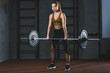 © LIGHTFIELD STUDIOS - Front view of young sportswoman exercising with barbell in sports hall