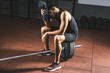 © LIGHTFIELD STUDIOS - Tired sportsman wiping face by towel and sitting on barbell in gym