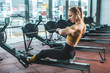 © LIGHTFIELD STUDIOS - Young sportswoman doing exercise on rowing machine in sports center