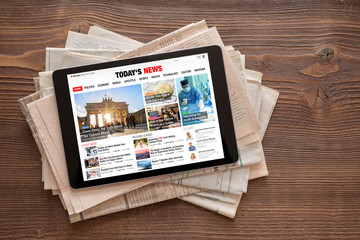 tablet with news website on stack of newspapers. all contents are made up.