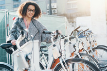 Afro American Woman Taking A Bicycle In A Bike Sharing Platform