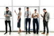 © pantovich - Group of businessmen with phones in their hands standing near the window