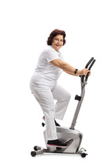 Sticker - Elderly woman exercising on a stationary bike and looking at the camera