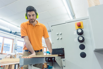 Carpenter working in furniture factory on computer controlled machine