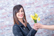 young brunette woman offers daffodils