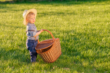 Wall Mural - Toddler child outdoors. One year old baby boy wearing straw hat with picnic basket