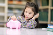 © Nattanon - Kids playing collect money with a pink saving Pig Jar in the Library. Setup studio shooting.