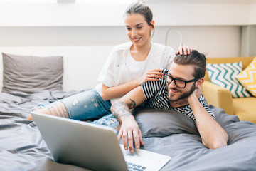 Wall Mural - Young couple watching a movie on their laptop in bed 