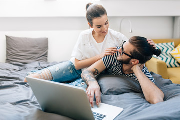 Wall Mural - Young couple watching a movie on their laptop in bed 