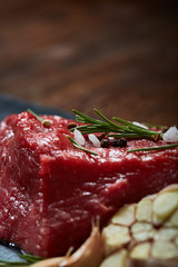 Sticker - Raw meat beef steaks on black slate board with spices, garlic and rosemary over wooden background, selective focus