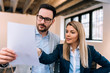 © bnenin - Close-up image of couple of business people examining documents. Talking while standing in office.