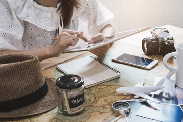 Wall Mural - Young woman planning vacation trip and searching information or booking hotel on a tablet