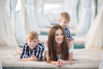 Wall Mural - Summer portrait of mother and two son on the beach. Happy family