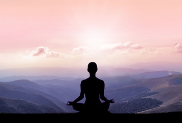 Yoga silhouette on the mountain in sunrays