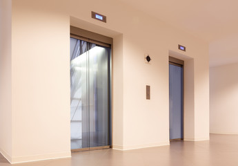 hallway with two elevators and a hall space with a curtain wall in office building