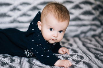 Wall Mural - Small baby boy lying on stomach and raising his head awhile looking surprised and smiling cute, newborn